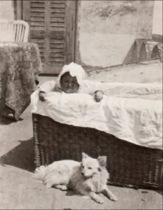 Die Spitzin Pipsi liegt wachsam und schützend vor einem Kleinkind (Foto von 1923)