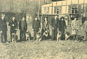 Die Wolfsspitz-Züchter in der DDR haben sich mit ihren Hunden auf dem Abrichteplatz im Halbkreis aufgestellt  ("Der Deutsche Spitz" Nr. 19, 1958)